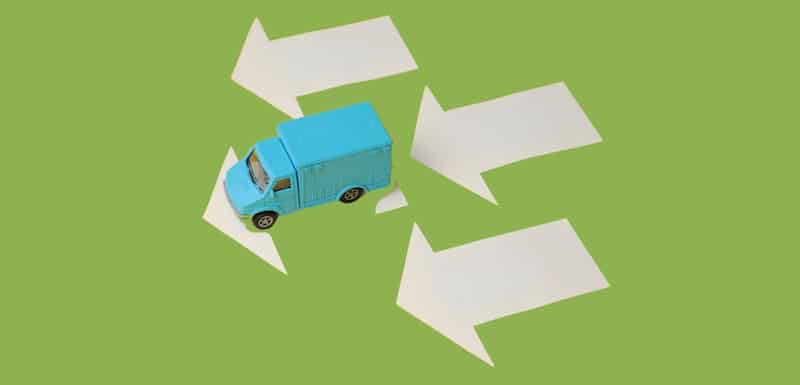 Toy Blue Truck driving on White Arrows Pointing Left Depicting Economy Shipping