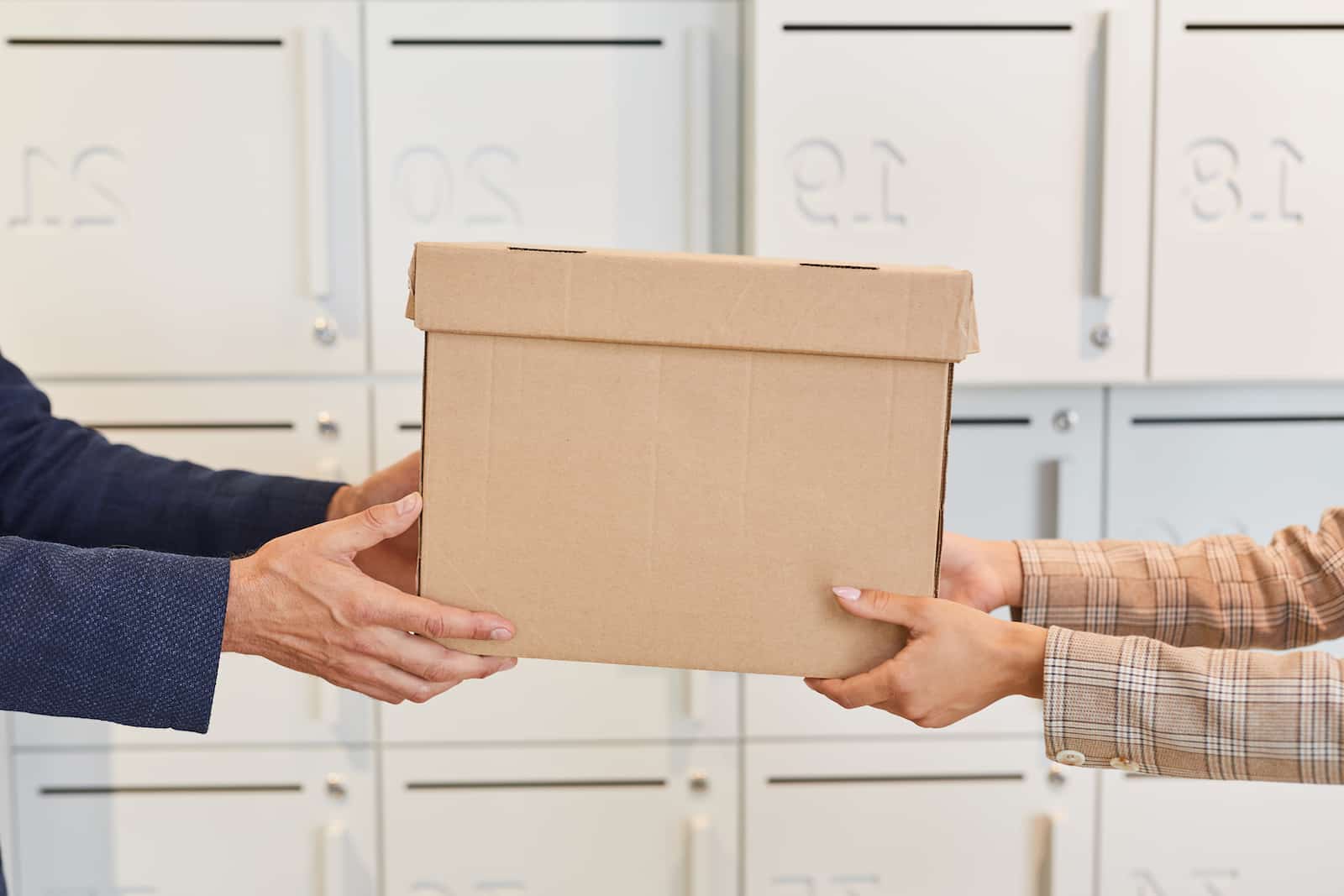 Two sets of hands holding a delivery box at the same time