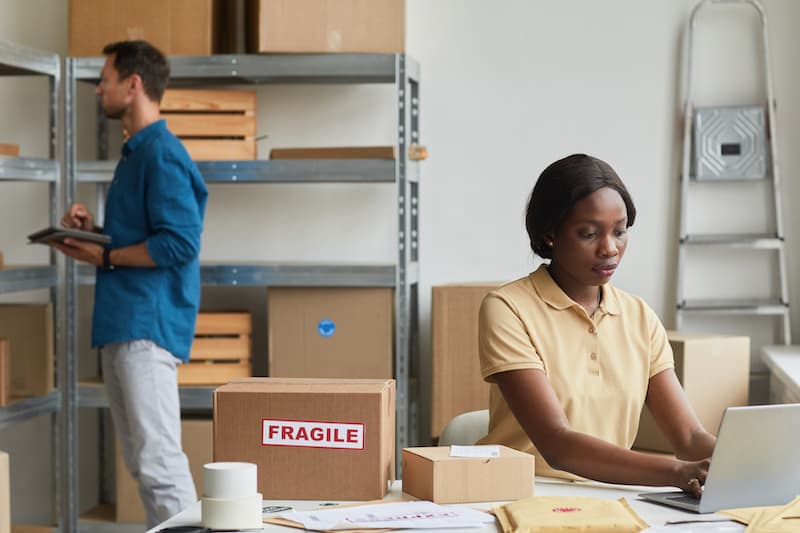 Small business shipping image of collegues in a warehouse preparing packages