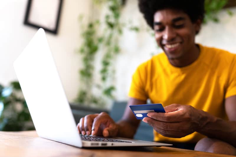 Smiling young man buying something online and enjoying his checkout page design