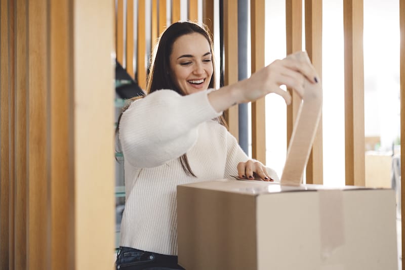 woman smiling while opening a package