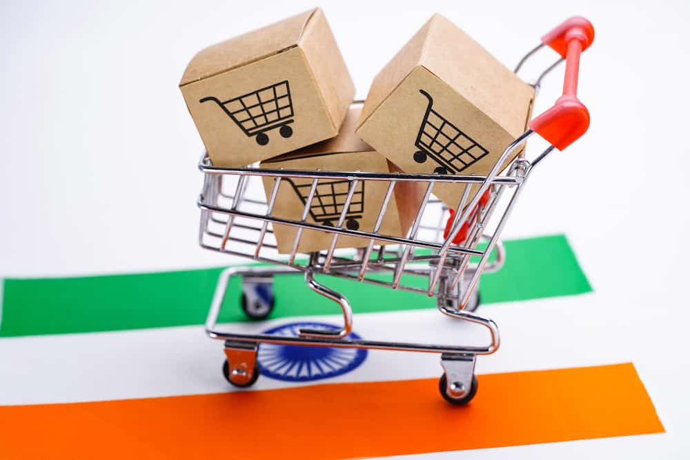 International Shipping from Canada to India concept photo with mini shopping cart and boxes on top of flag of India