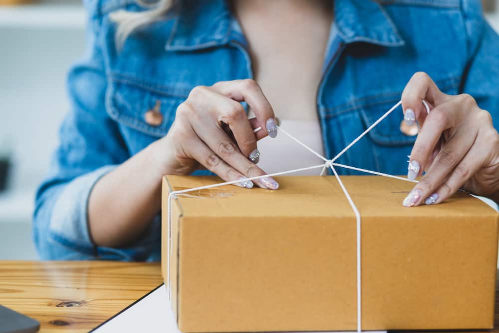 person wrapping a box with string