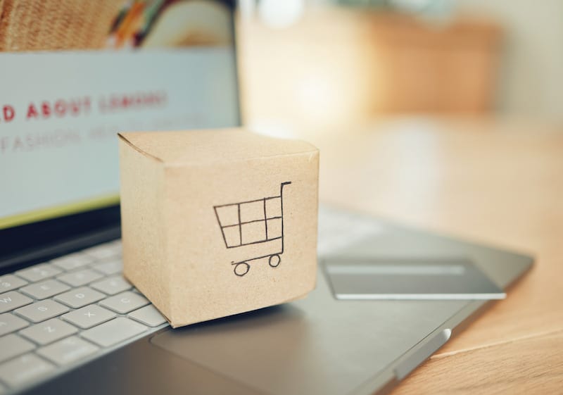 Online shipping apps concept photo box with shopping cart on it on top of a laptop